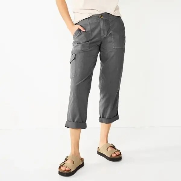 Female model wearing charcoal grey cropped cargo pants with rolled cuffs and side cargo pocket, paired with beige sandals